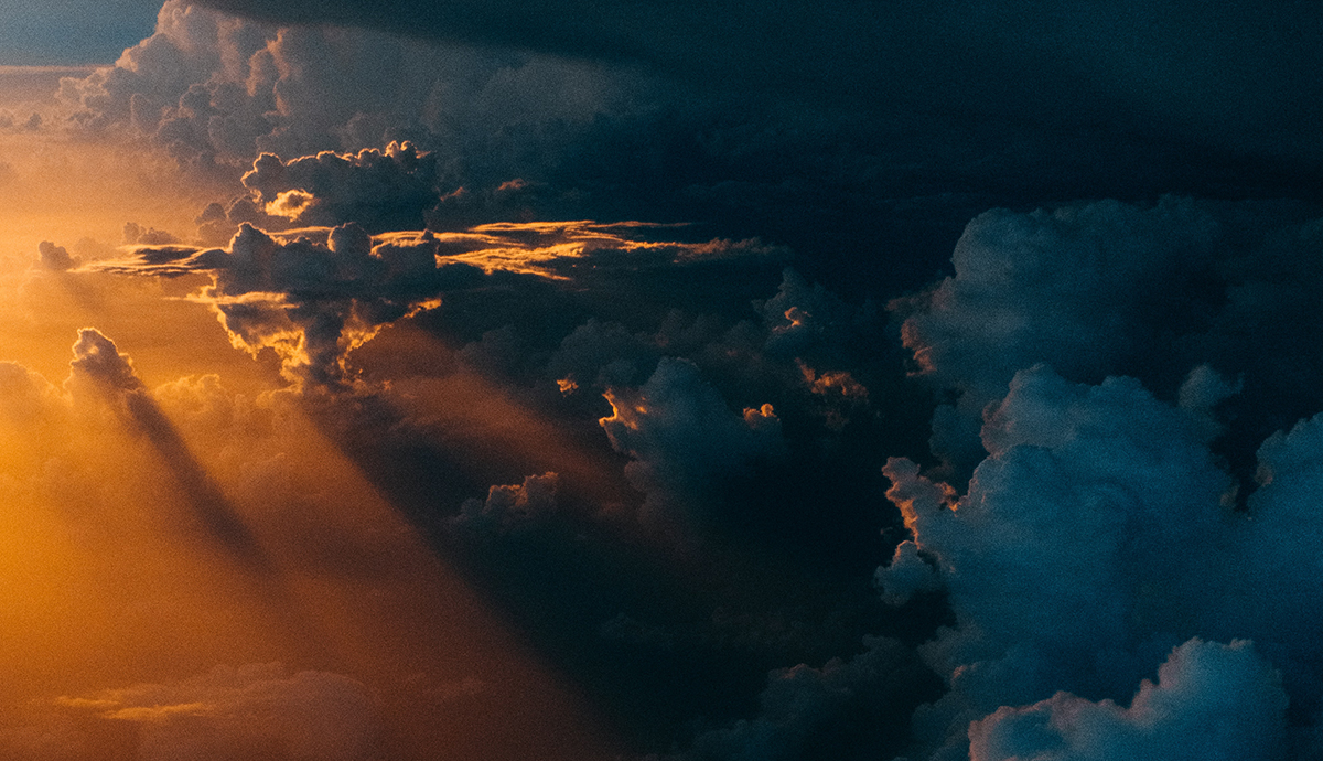 Header Graphic: Sunlight peaking out of the clouds from the view of a drone | Image Credit: Tom Barrett via Unsplash