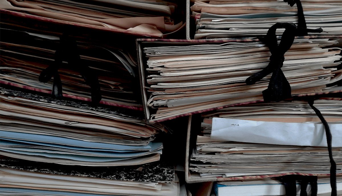 Header Graphic: A stacks of papers and folders held together with string | Image Credit: Unsplash