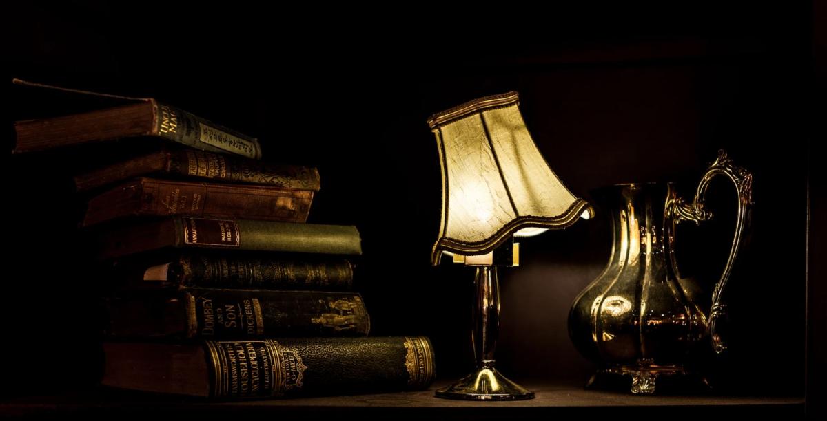 lamp and books on a table, lampshade is crooked