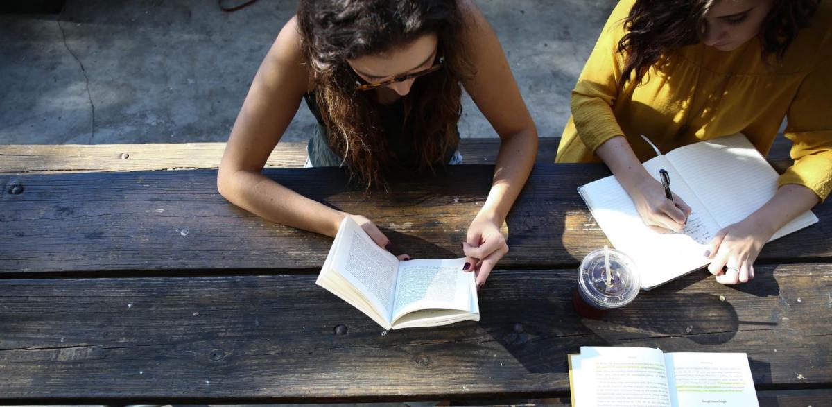 Image of women reading and writing at a table courtesy of Unsplash