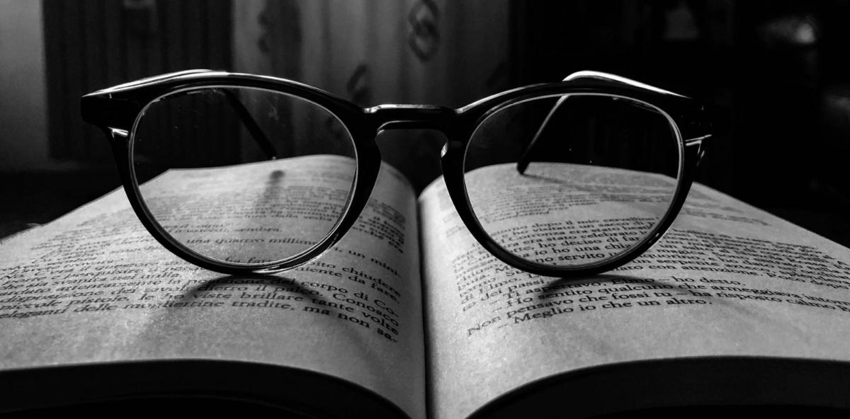 black and white image of glasses resting on an open book