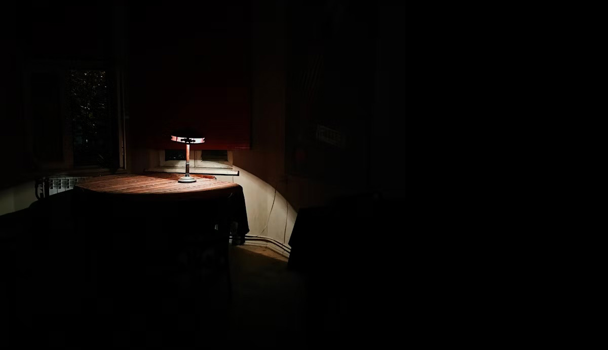 lamp illuminating a table in a very dark room | unsplash