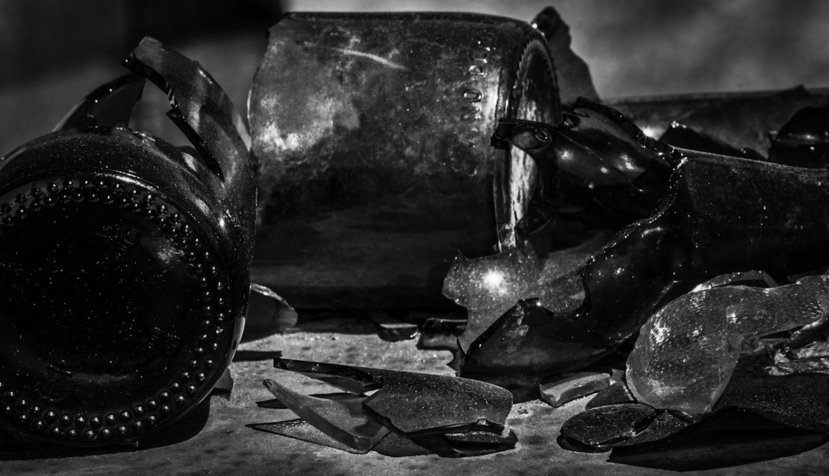 A black and white image of a variety of broken bottles