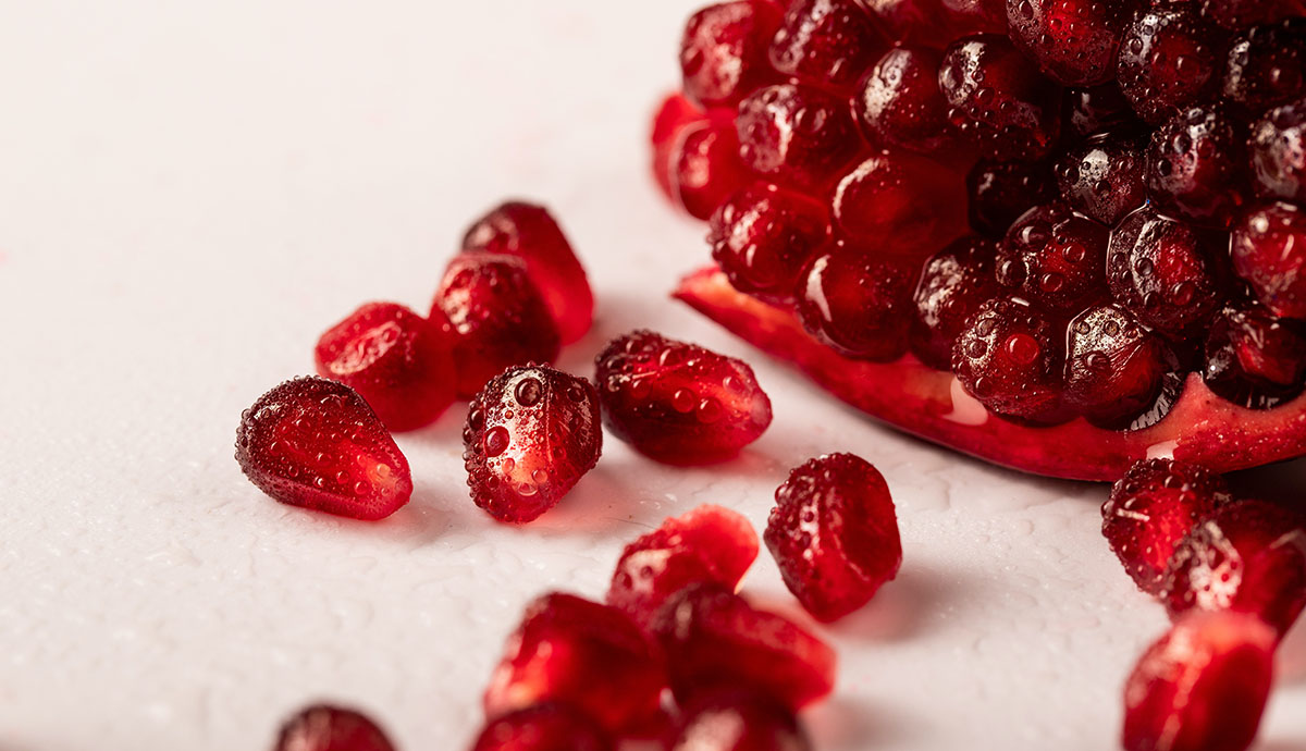 Header Graphic: Pomegranate seeds spilling onto a white background