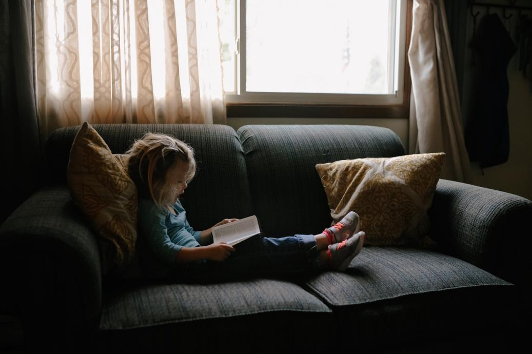 Young girl reading on couch