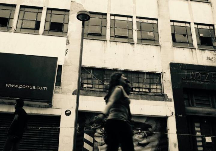 Juarez, a photo by Nicolas Poynter. It shows people passing by in front of a building.