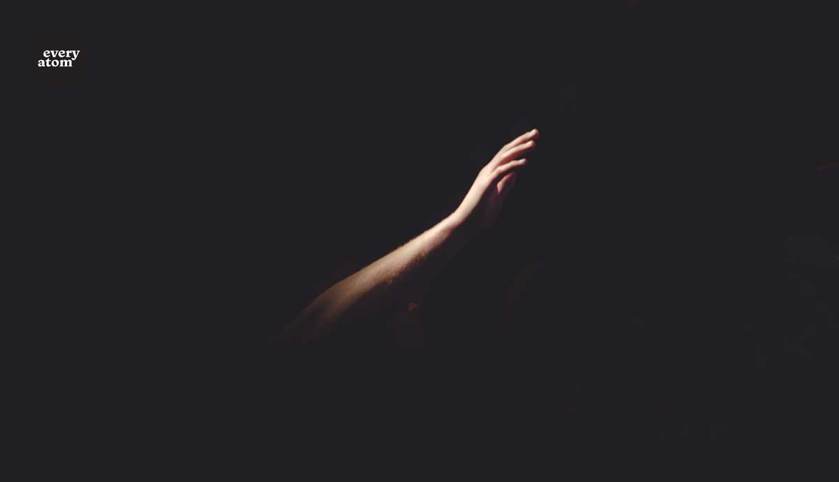 A hand reaching out in darkness
