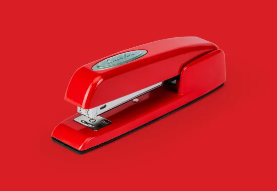 Red stapler on red background