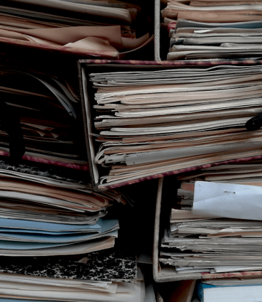 Header Graphic: A stacks of papers and folders held together with string | Image Credit: Unsplash
