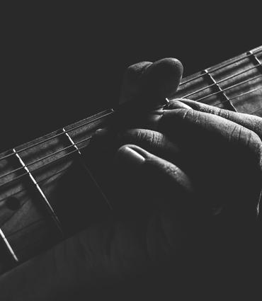 Header Graphic: Grayscale close up on a jazz guitar player | Image Credit: Caio Silva via Unsplash