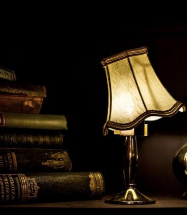 lamp and books on a table, lampshade is crooked