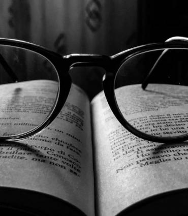 black and white image of glasses resting on an open book