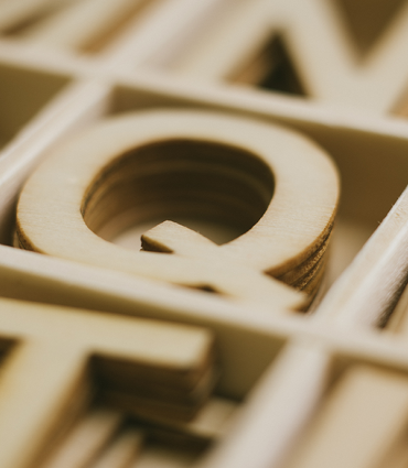Wooden Q in box of wooden letters