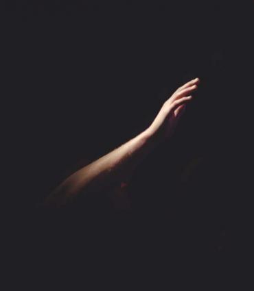 A hand reaching out in darkness