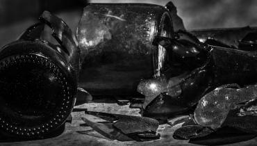 A black and white image of a variety of broken bottles