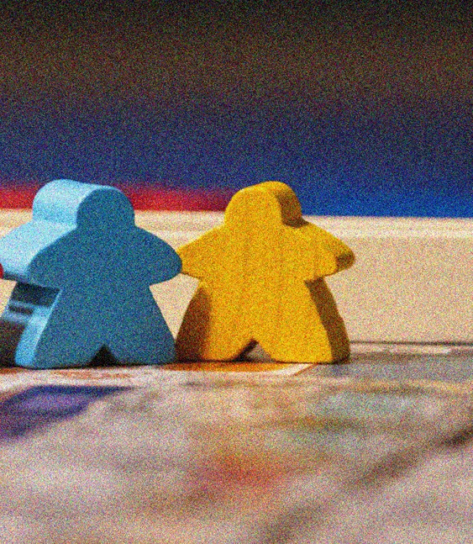Three wooden Lego blocks stand behind a wooden train set. The blocks are red, blue, and yellow.