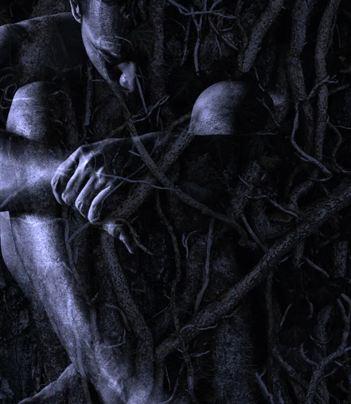 Huddled figure among roots