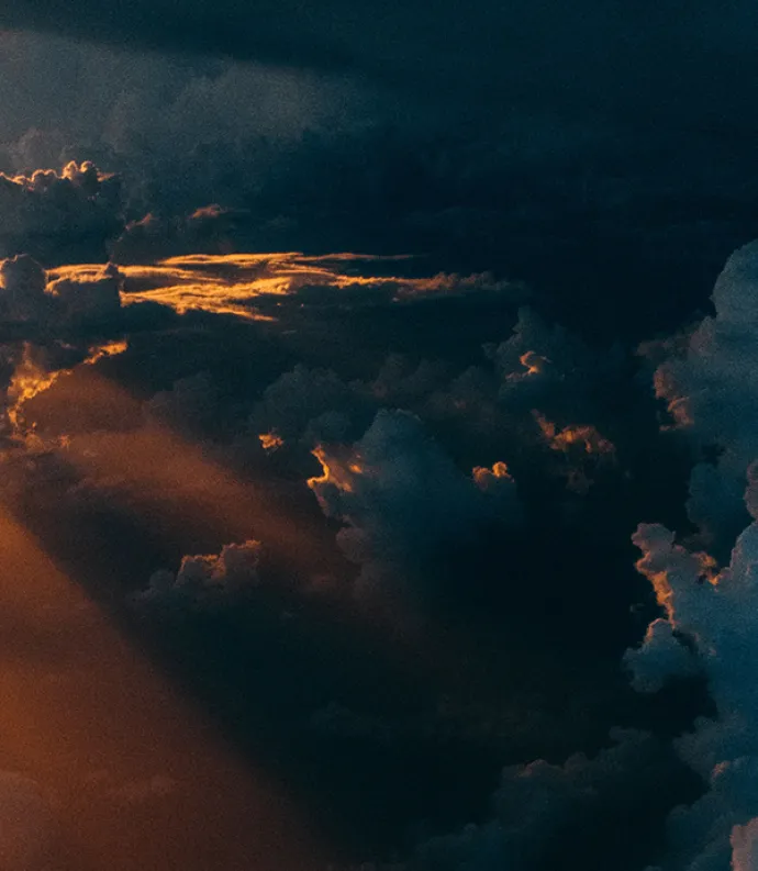 Header Graphic: Sunlight peaking out of the clouds from the view of a drone | Image Credit: Tom Barrett via Unsplash