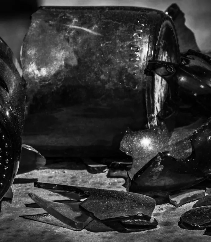 A black and white image of a variety of broken bottles