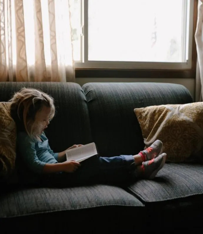 Young girl reading on couch